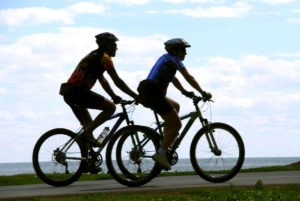Two men riding bicycles on sea shore trail, motion blur, trail is in focus