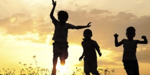 Children running on meadow at sunset